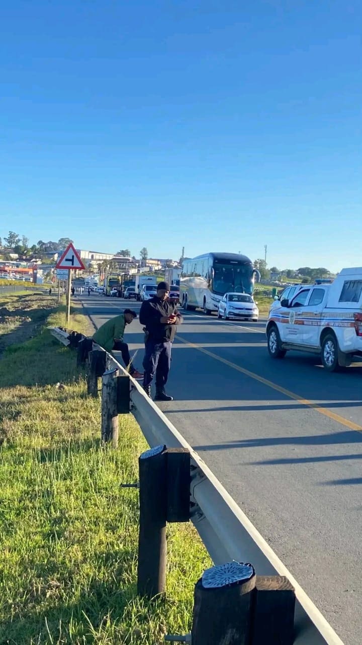 Idtya Aciden Taxis block the N2 near Dutywa during a protest over disputes with bus services. Law enforcement officers redirect traffic.